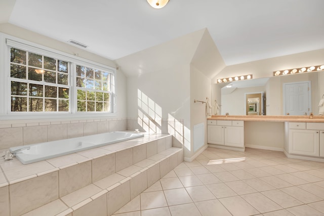 bathroom with tile patterned floors, tiled bath, vanity, and lofted ceiling