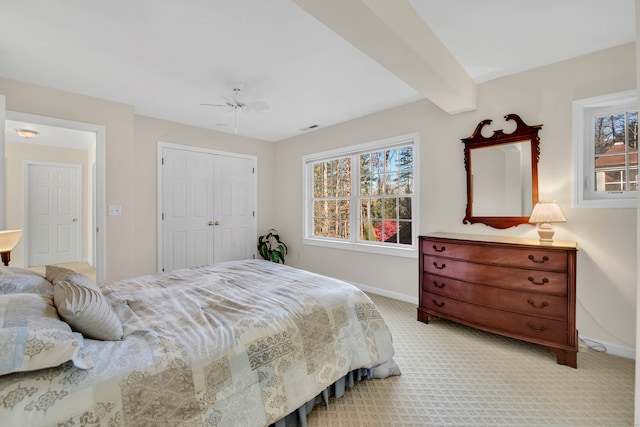 bedroom featuring multiple windows, ceiling fan, a closet, and light colored carpet