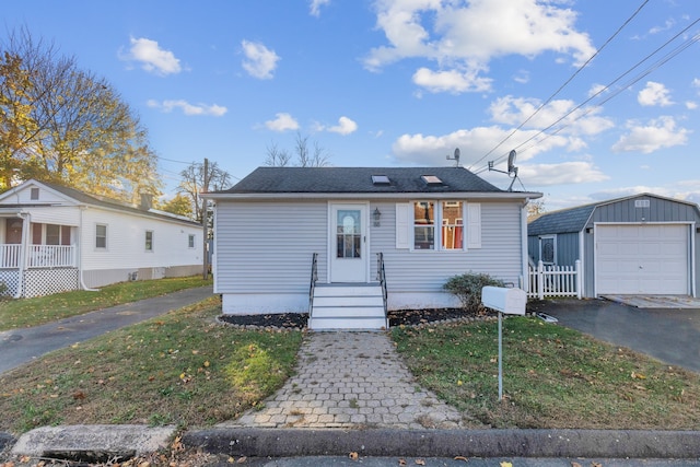 bungalow-style home featuring an outbuilding, a garage, and a front lawn