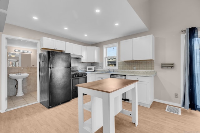 kitchen with light hardwood / wood-style flooring, white cabinetry, and black appliances