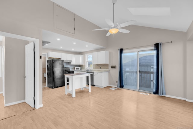 kitchen featuring black fridge, a kitchen island, light hardwood / wood-style floors, white cabinetry, and a breakfast bar area