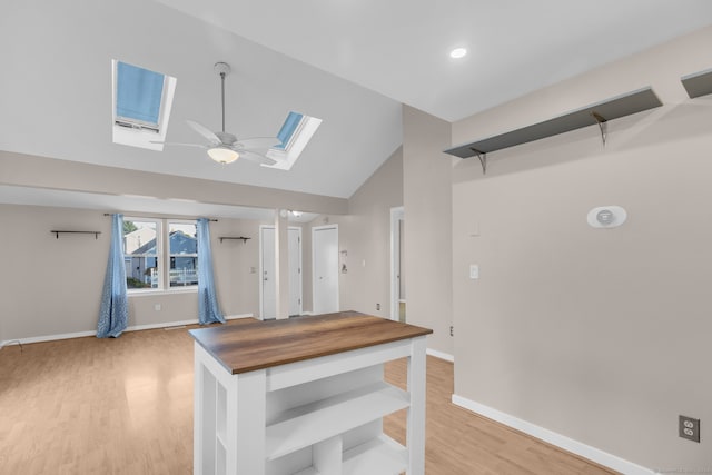 interior space featuring vaulted ceiling with skylight, ceiling fan, and light wood-type flooring