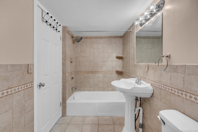 bathroom with tile patterned floors, tiled shower / bath combo, tile walls, and toilet