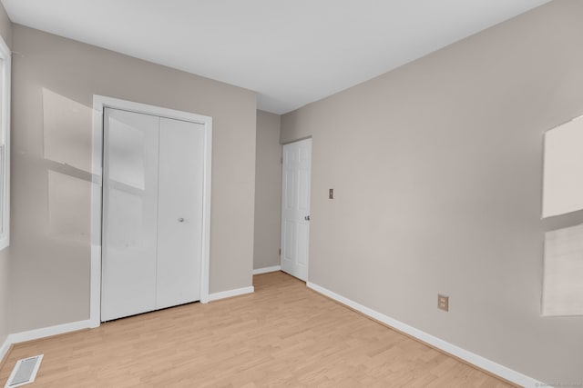 unfurnished bedroom featuring light wood-type flooring and a closet