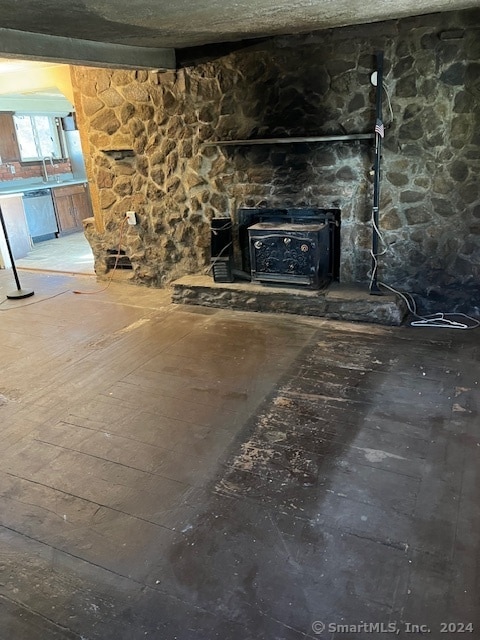 unfurnished living room featuring wood-type flooring and a wood stove