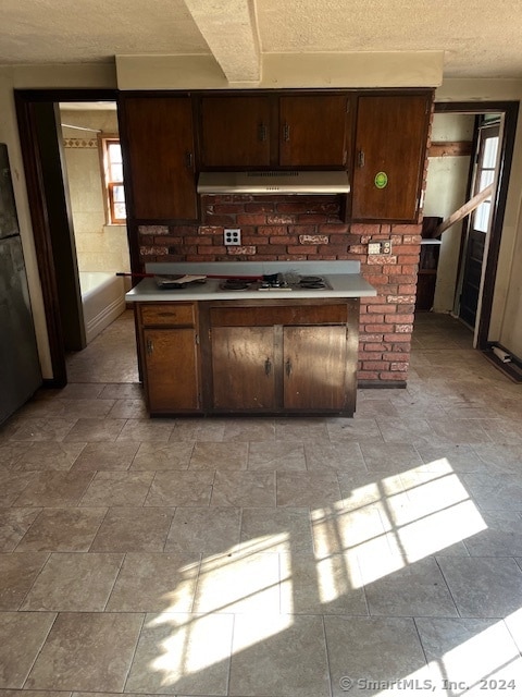 kitchen with white gas stovetop, stainless steel refrigerator, and dark brown cabinets