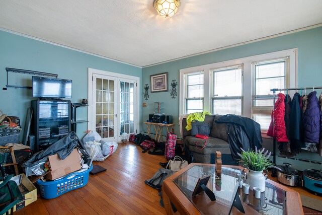living room featuring french doors, hardwood / wood-style floors, a healthy amount of sunlight, and crown molding