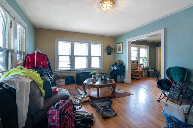 living room featuring light hardwood / wood-style floors, baseboard heating, cooling unit, and ornamental molding