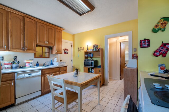 kitchen featuring light tile patterned floors, white appliances, and sink