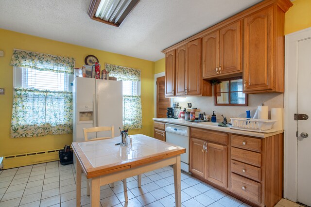 kitchen featuring baseboard heating, a textured ceiling, light tile patterned floors, white appliances, and tile counters