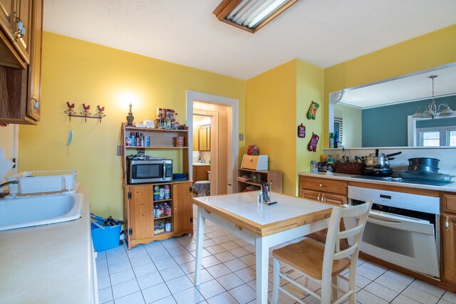 kitchen featuring light tile patterned flooring, an inviting chandelier, sink, and white oven
