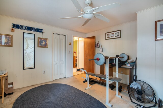 exercise area with wood walls and ceiling fan