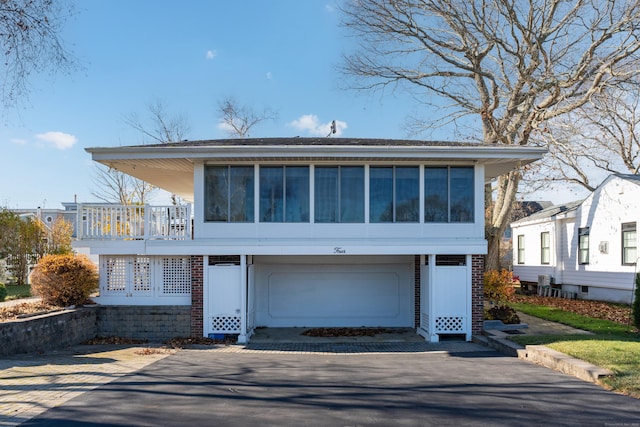 view of front of house with a garage, a sunroom, and driveway