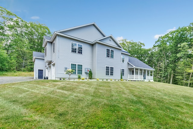 back of property featuring covered porch, a garage, and a lawn