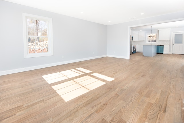 unfurnished living room featuring a chandelier and light hardwood / wood-style floors