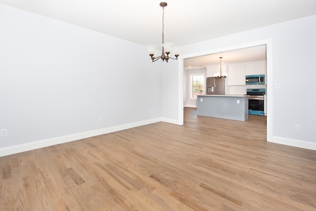 unfurnished living room featuring a chandelier and light hardwood / wood-style flooring