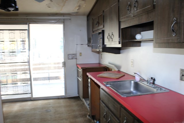 kitchen featuring concrete flooring, dark brown cabinets, sink, and black microwave