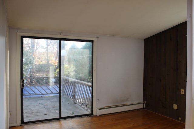 spare room with hardwood / wood-style floors, wood walls, and a baseboard heating unit