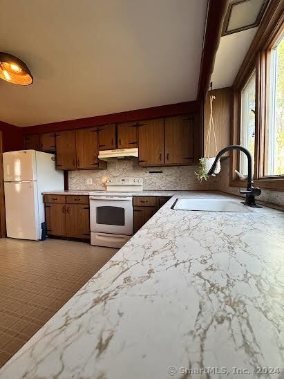 kitchen with backsplash, white appliances, and sink