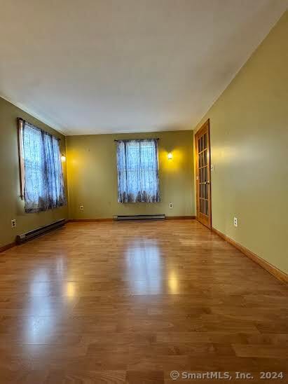 spare room featuring a baseboard heating unit and hardwood / wood-style flooring