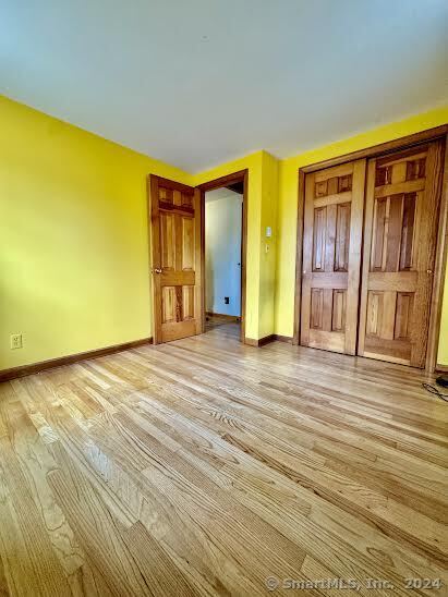 unfurnished bedroom with light hardwood / wood-style flooring and a closet