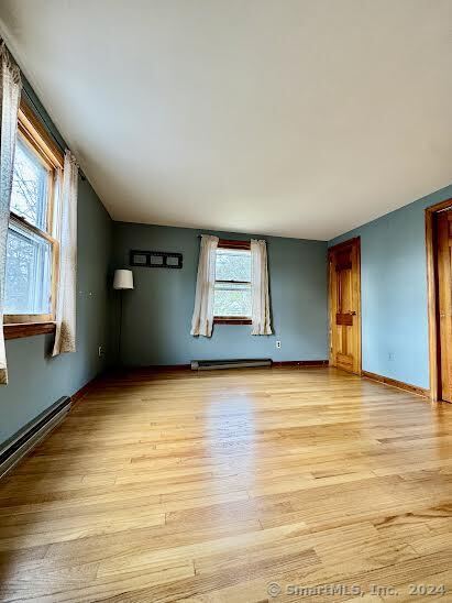 empty room with light hardwood / wood-style floors and baseboard heating