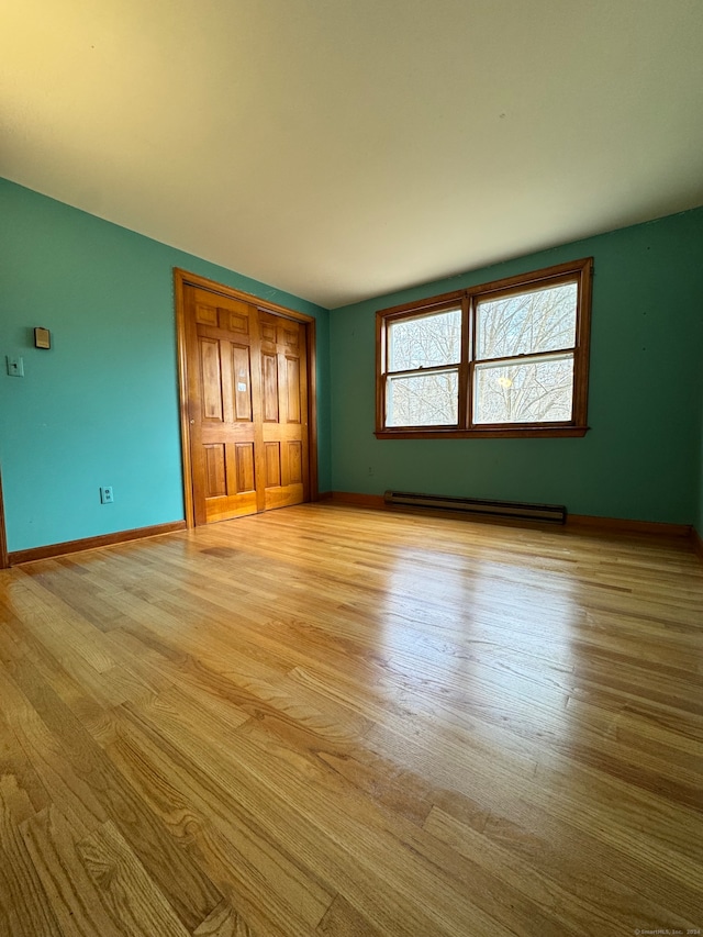 unfurnished bedroom featuring light wood-type flooring and a baseboard radiator