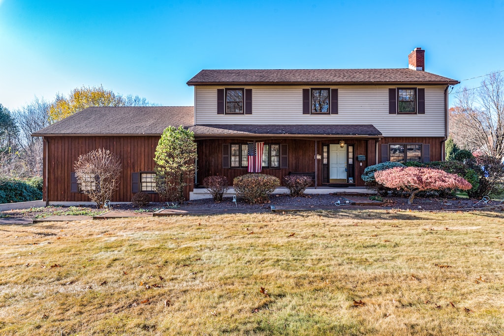 view of property with covered porch and a front lawn