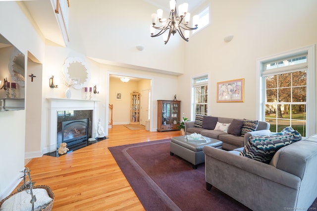 living room featuring hardwood / wood-style floors, a notable chandelier, and a towering ceiling