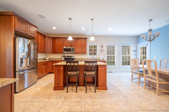 kitchen with a center island, appliances with stainless steel finishes, light stone counters, and hanging light fixtures