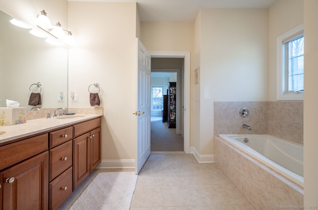 bathroom featuring tile patterned flooring, vanity, and tiled tub