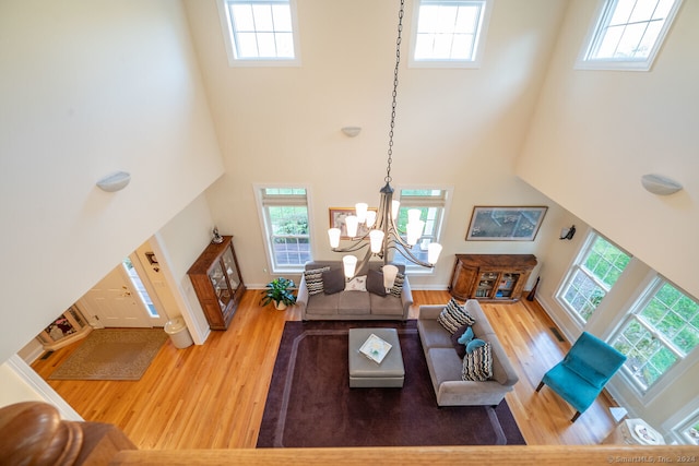 living room with a high ceiling, wood-type flooring, and a notable chandelier