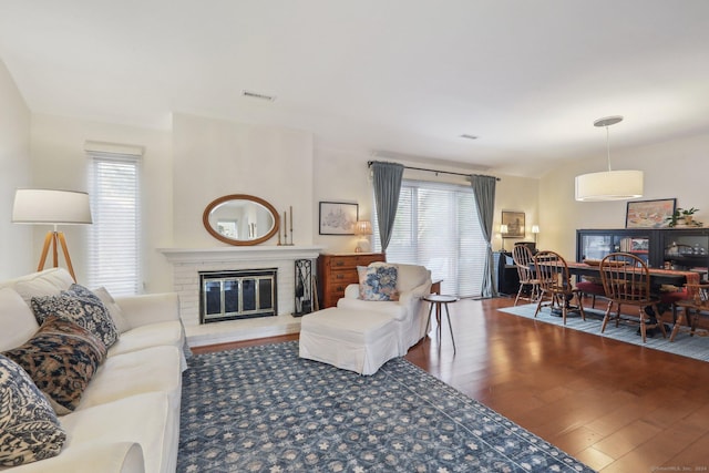 living room with plenty of natural light, wood-type flooring, and a brick fireplace