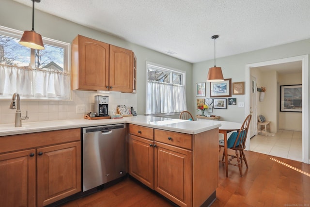 kitchen featuring dishwasher, sink, kitchen peninsula, and hanging light fixtures