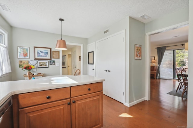 kitchen featuring dishwasher, hanging light fixtures, a textured ceiling, and hardwood / wood-style flooring