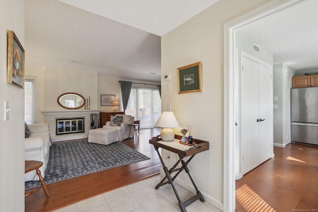 living room with light hardwood / wood-style floors and a brick fireplace