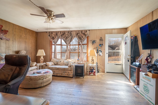 living room featuring light hardwood / wood-style floors, ceiling fan, and wooden walls