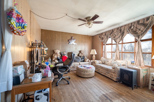 living room featuring wood walls, ceiling fan, and wood-type flooring