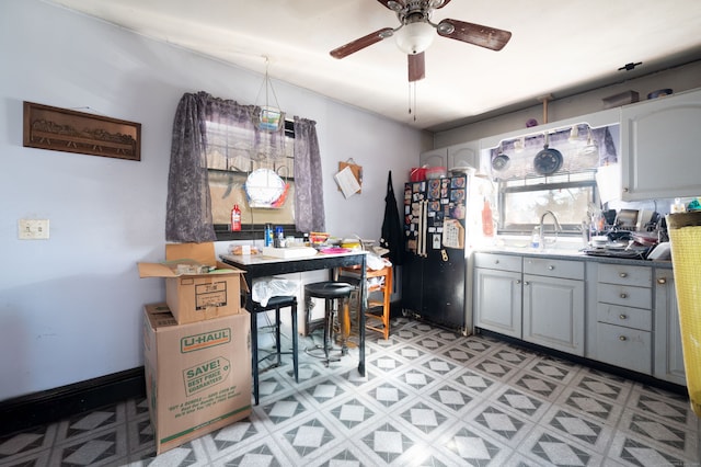 kitchen with black fridge, ceiling fan, gray cabinetry, and sink