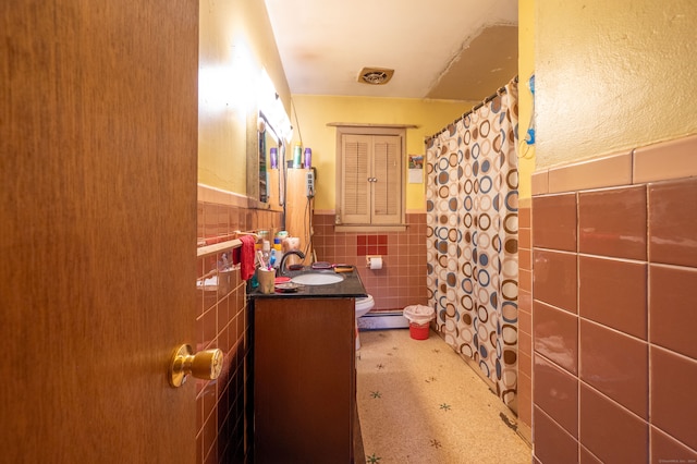 bathroom featuring vanity, tile walls, and toilet