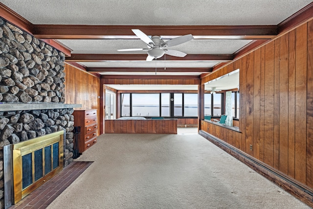 unfurnished living room featuring beamed ceiling, wood walls, a textured ceiling, and dark carpet