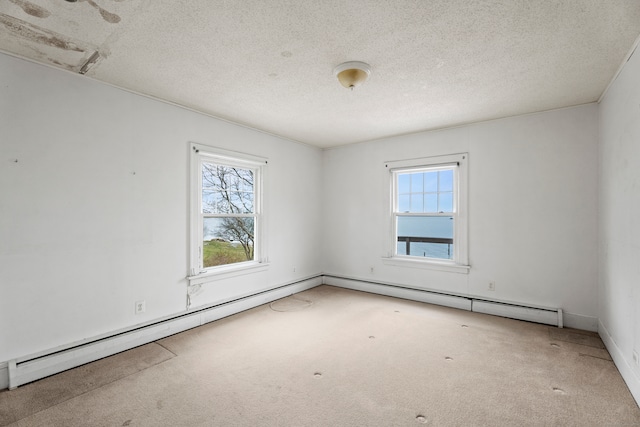 carpeted spare room featuring a wealth of natural light, a textured ceiling, and a baseboard heating unit