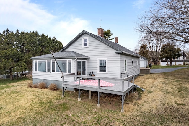 rear view of property featuring a sunroom, a wooden deck, and a lawn