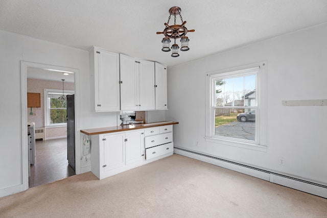 kitchen featuring a baseboard radiator, black fridge, butcher block countertops, light carpet, and white cabinets