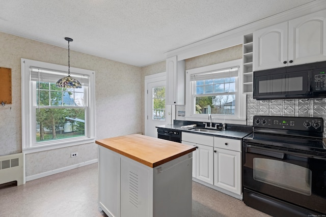 kitchen with radiator, white cabinetry, butcher block counters, hanging light fixtures, and black appliances