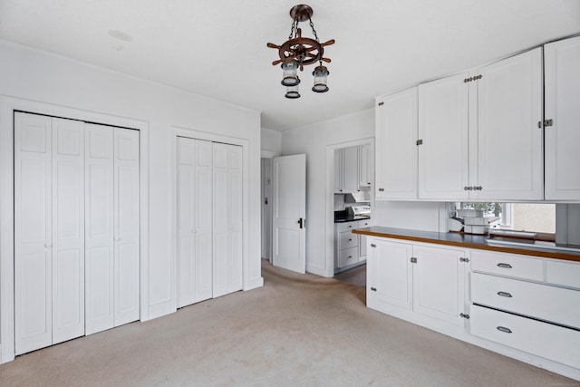 kitchen featuring white cabinets, butcher block counters, and light carpet