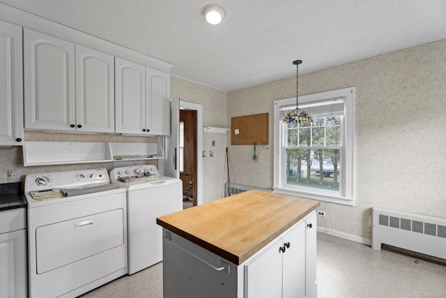 laundry area with washing machine and clothes dryer, radiator, cabinets, and a textured ceiling