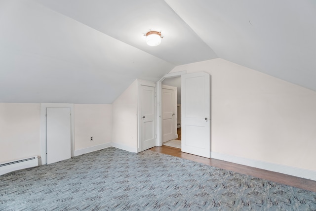 additional living space with light wood-type flooring, a baseboard radiator, and vaulted ceiling