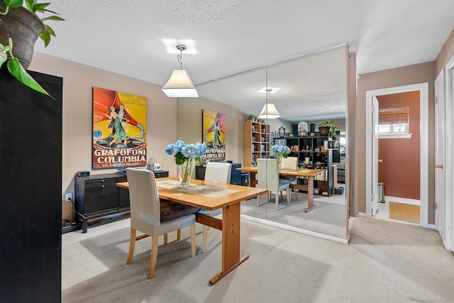 dining room with light colored carpet and a textured ceiling