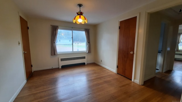 unfurnished dining area featuring radiator and hardwood / wood-style flooring